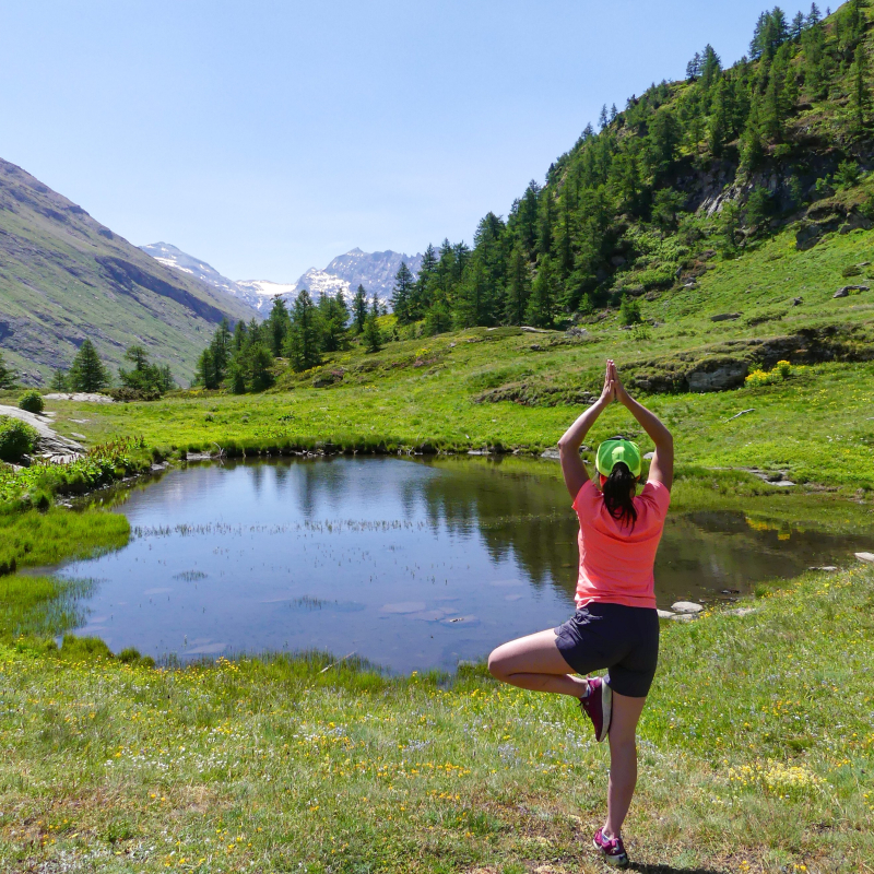 Woman in yoga position in front of a high-altitude lake