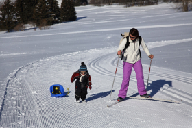 Enfant avec luge et sa maman en ski de fond sur le Plateau des Mouilles