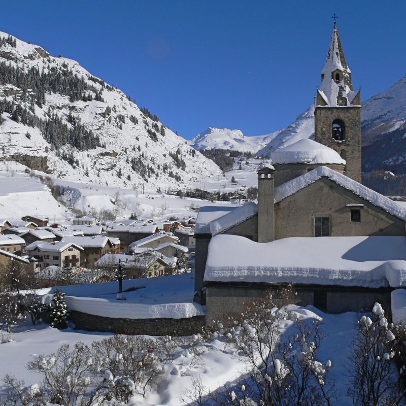 View of the church and the snowy village of Val Cenis Lanslevillard